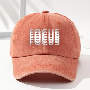 Vintage washed orange baseball cap with FOCUS print shown in a minimalist studio setting
