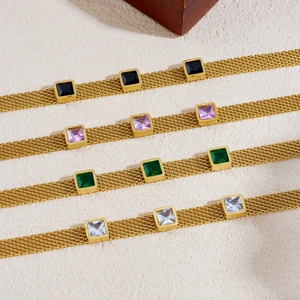 Golden mesh chain bracelets with colorful square gemstones on a stone background