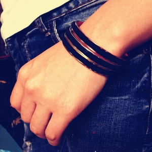 Close-up of minimalist gold and black stackable cuff bracelets on a person wrist
