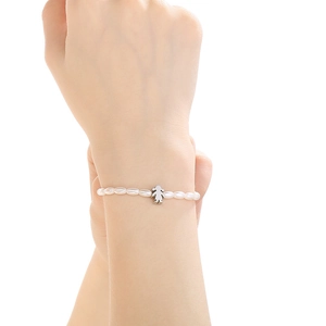Detail of elegant white pearl bead bracelet with a silver girl-shaped charm on wrist