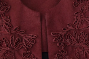 Close-up of burgundy knit fabric with detailed 3D floral embroidery on the neckline
