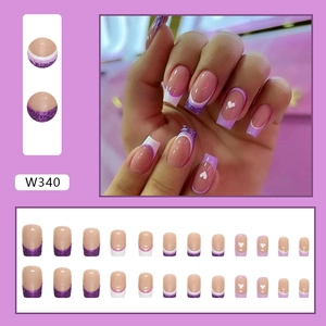 Detailed view of purple French press-on nails with glitter tips and heart patterns.