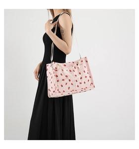 Detail of pink corduroy tote bag with strawberry print and adjustable crossbody strap