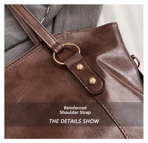 Detail view of reinforced shoulder strap on brown leather tote with gold hardware