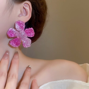 Macro shot of elegant oversized pink rhinestone flower earrings on a fashion model