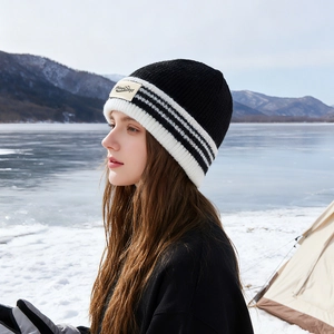 Bonnet en maille rayé unisexe avec logo PineCrest devant un paysage de montagne enneigé