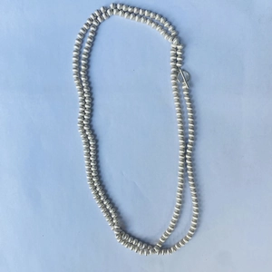 Détail du collier à perles argentées avec texture brossée et fermoir à bascule