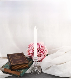 Elegant glass candle holder with spherical stem on vintage books with roses