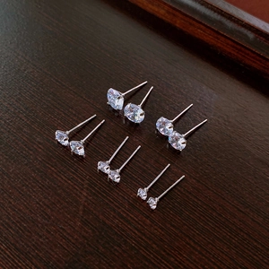 Five pairs of minimalist cubic zirconia silver studs in various sizes on wood