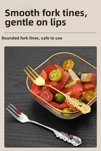 Detailed close-up of rose relief handles on gold and silver stainless steel fruit forks