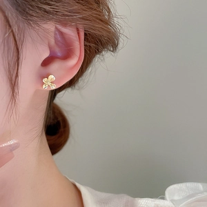 Gros plan d'une petite puce d'oreille en forme de fleur dorée sur le lobe d'une femme