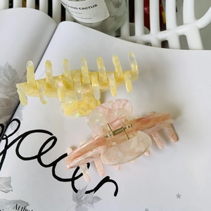 Detail of colorful acetate hair claws in yellow and pink marble on a magazine page