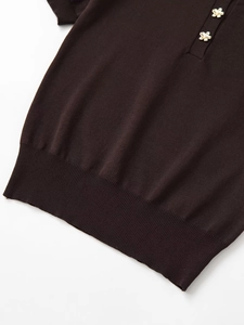 Detail of dark coffee knit polo shirt featuring decorative golden flower buttons