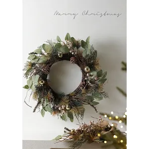 Nordic Christmas wreath with pine cones and white berries hanging on a white wall decor