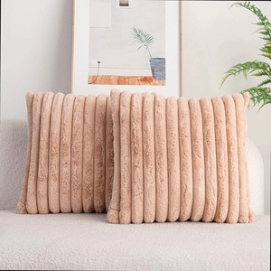 Close-up of pink faux rabbit fur throw pillows with striped texture on a cozy sofa