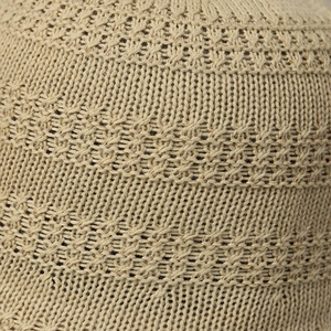 Macro detail of the beige knitted fabric showing hollow texture and premium crochet pattern