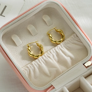 Detail of 18k gold plated twisted hoop earrings inside a pink leather jewelry gift box