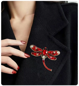 Detail of vintage dragonfly brooch with red crystals pinned on a black coat lapel