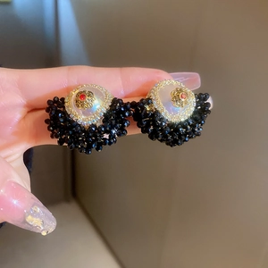 Detail of vintage flower earrings with pearl studs and black beaded tassels in gold finish