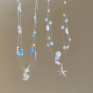 Détail de pendentifs étoile de mer et coquillage sur colliers de perles pour la plage