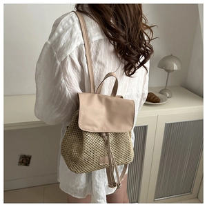 Detail of woven straw backpack showing the leather flap closure and mixed material texture