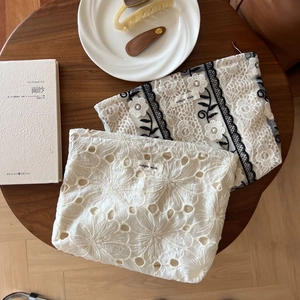 Detail of white lace embroidery and mesh fabric cosmetic bags on a wooden table