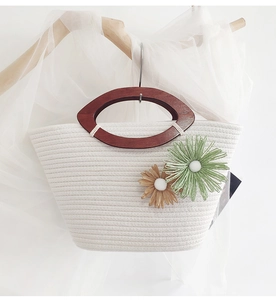 Detail of hand-woven cotton bag with wooden handles and floral crochet accents