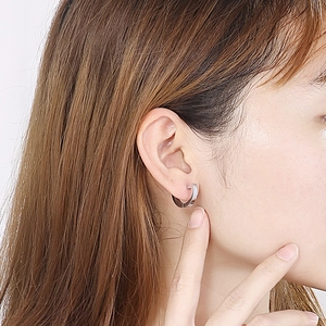 Close-up of minimalist silver geometric U-shaped hoop earring worn on female ear