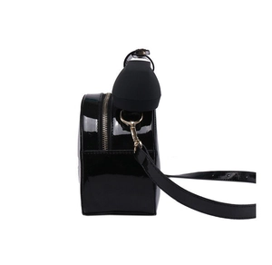 Detail view of black patent leather phone bag with shiny finish and gold zippers
