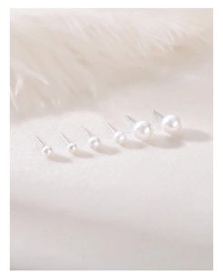 Macro shot of S999 sterling silver pearl earrings in various sizes on soft fabric