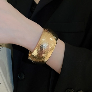 Detailed view of wide gold hammered cuff bracelet with textured metallic finish