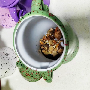 Top view of green ceramic canister with speckled glaze filled with dried herbal spices