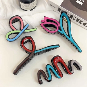 Set of four colorful tulip-inspired hair claws with abstract wave designs on white surface