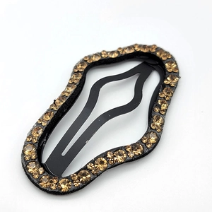 Close-up of cloud-shaped hair clip with champagne rhinestones on black base