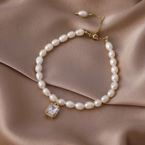 Detail of baroque freshwater pearl bracelet with gold hardware and zircon pendant