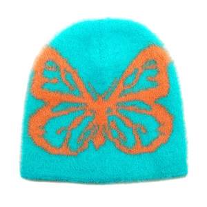 Detail shot of the fuzzy plush texture and orange butterfly pattern on teal beanie