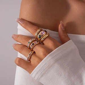 Close-up of gold-plated geometric rings set with vibrant colored zircon stones on hand