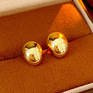 Close-up of gold-plated egg-shaped mirror studs in a brown velvet jewelry box