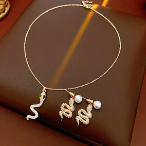 Dettaglio del set collana con ciondolo a serpente dorato e orecchini di perle con zirconi