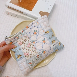 Detail of floral quilted cotton makeup bag with metal zipper and soft blue pattern