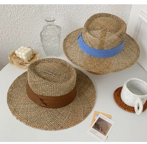 Detail shot of straw sun hats with blue and brown ribbons in a beach holiday setting