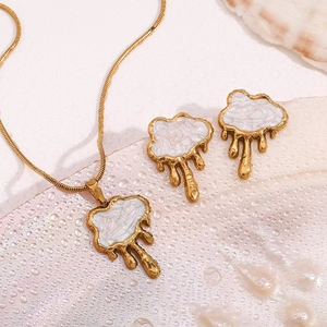 Detailed set of 18K gold plated jewelry with cloud fluid charms on a seashell surface