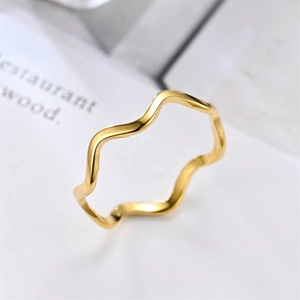 Minimalist wavy stainless steel ring in gold finish on a clean white magazine background