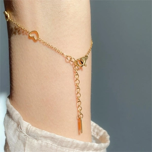 Detailed view of a gold heart charm bracelet on wrist with elegant lobster clasp and chain