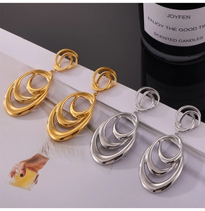 Macro detail of intertwined gold and silver geometric oval hoop earrings on a magazine
