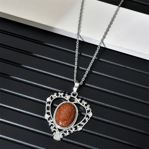 Detail of silver heart pendant with reddish-brown goldstone on striped background