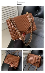 Detail of brown quilted crossbody bag with chevron stitching and gold chain strap