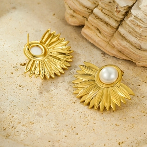 Vintage stainless steel sunburst fan earrings with white pearl center on a stone texture