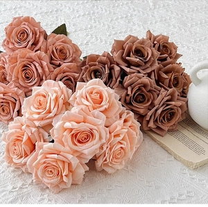 Silk artificial roses in peach, dusty pink, and caramel on a white lace tablecloth