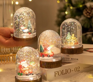 Close-up of Christmas snow globes featuring Santa Claus and snowman motifs on wood base
